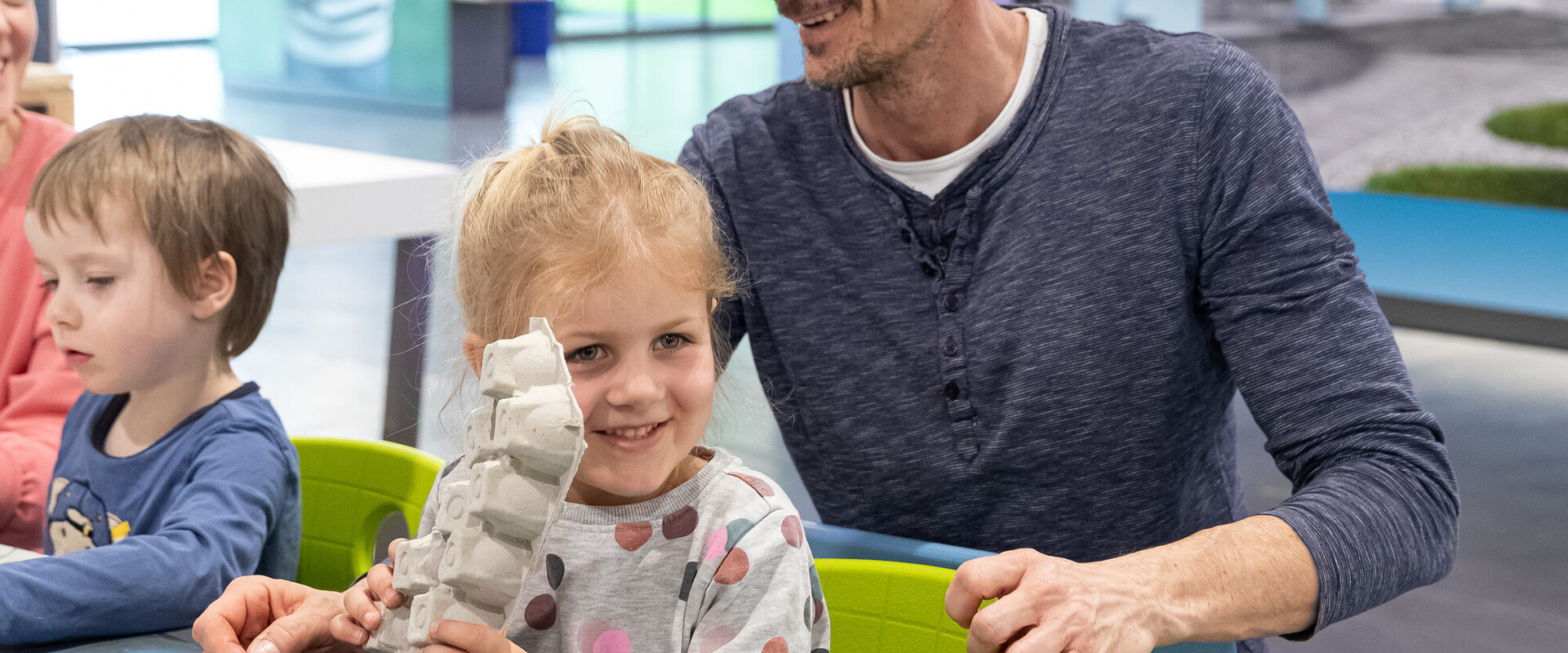 Kinder mit Vater basteln in der Kreativwerkstatt.